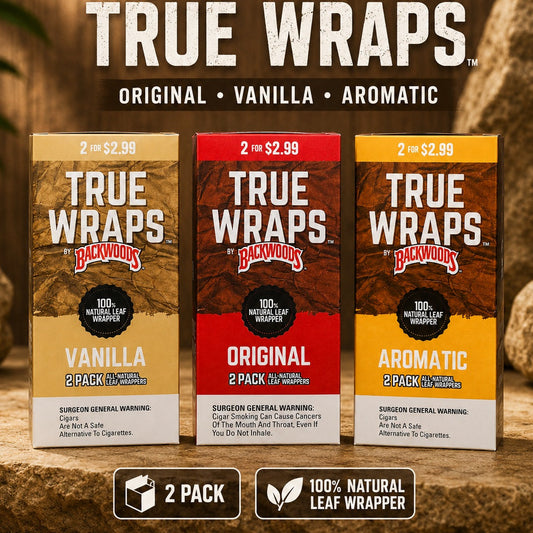 Three Backwoods by Paper Dog True Wraps 2-pack boxes shown on a rustic wood background with rocks. The packages are labeled Vanilla, Original, and Aromatic, 